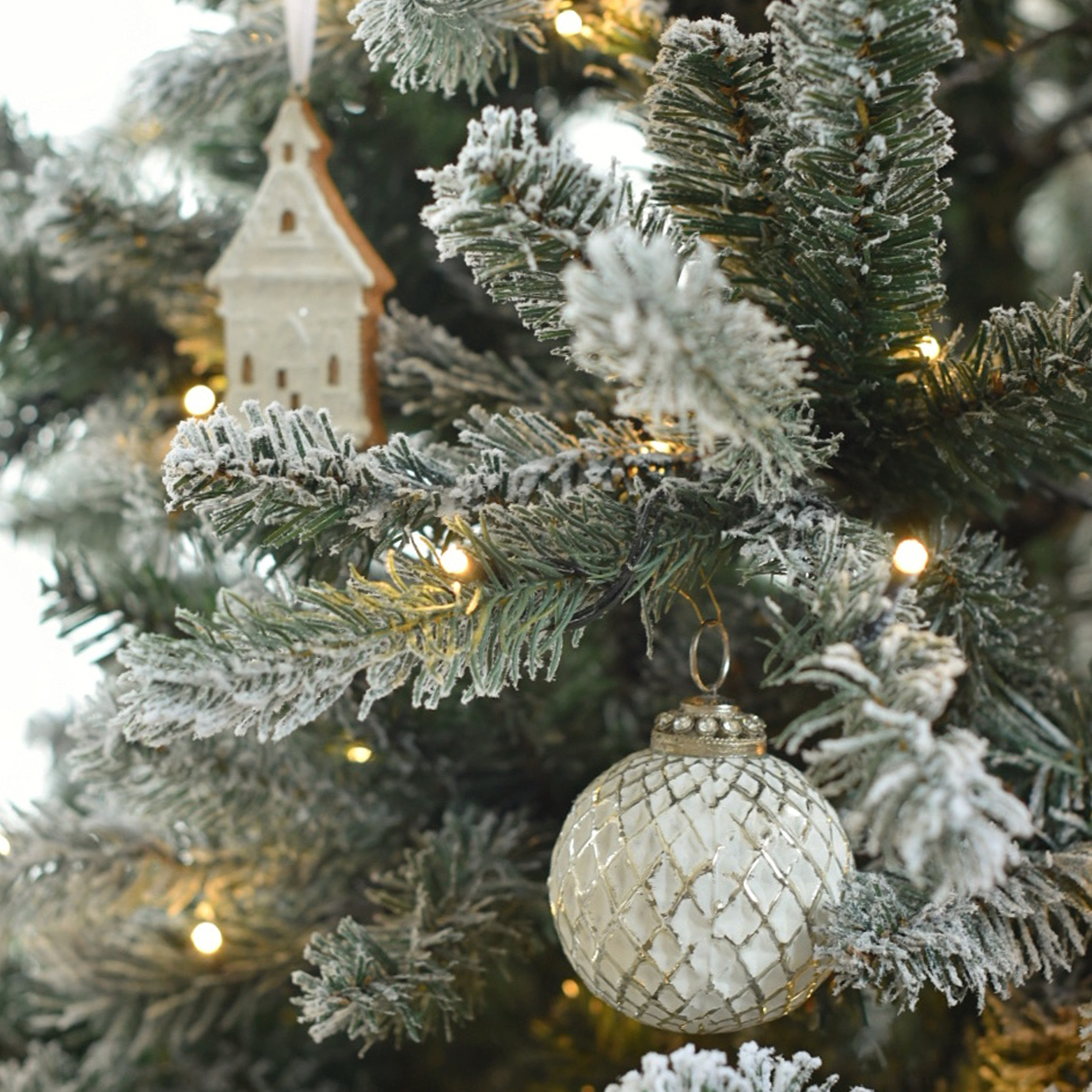 Bola de Navidad blanca de cristal con patrón de rejilla en árbol nevado con luces LED y adorno de madera