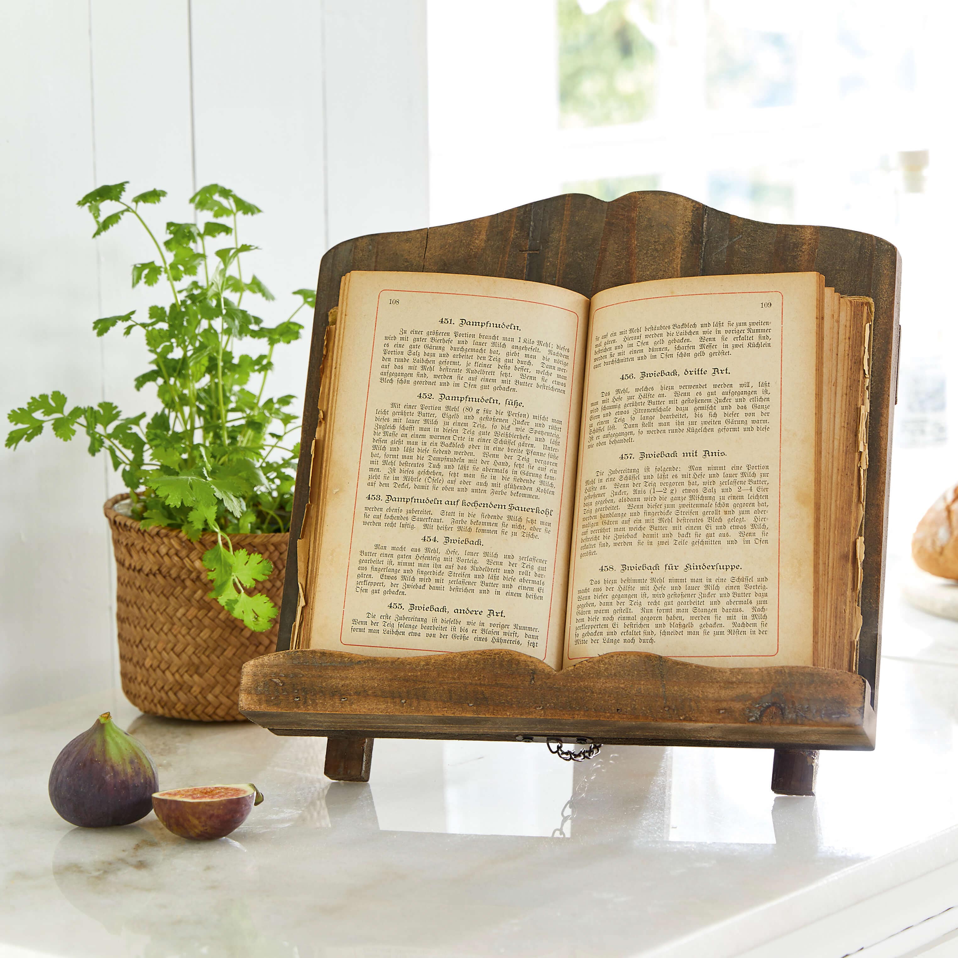 Soporte de libro de madera oscura con libro de cocina antiguo abierto sobre encimera de mármol