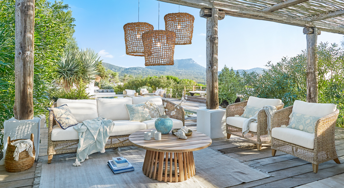 Conjunto de muebles de jardín de ratán natural con cojines blancos y mesa de madera redonda