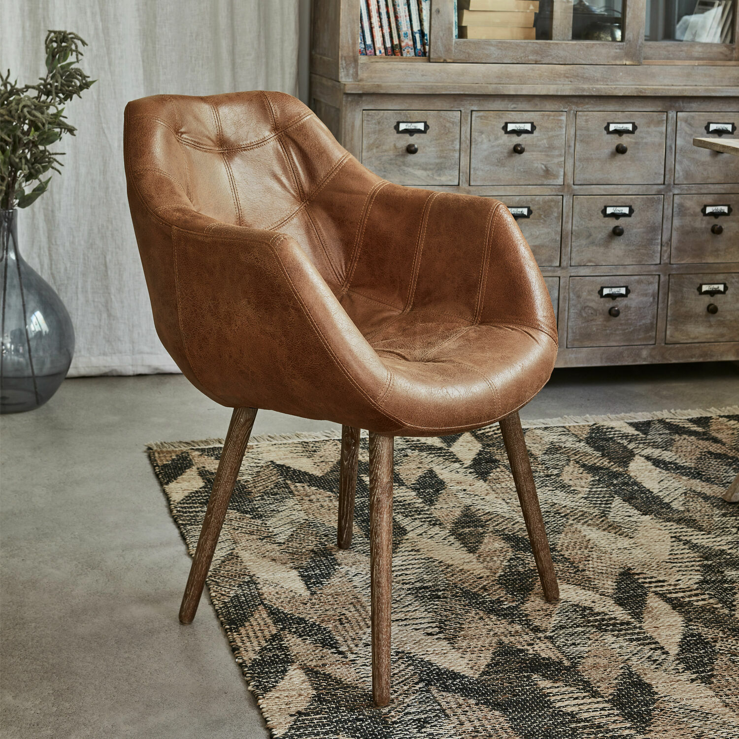Silla Montigny Sillón marrón de cuero sintético con patas de madera sobre alfombra geométrica en sala