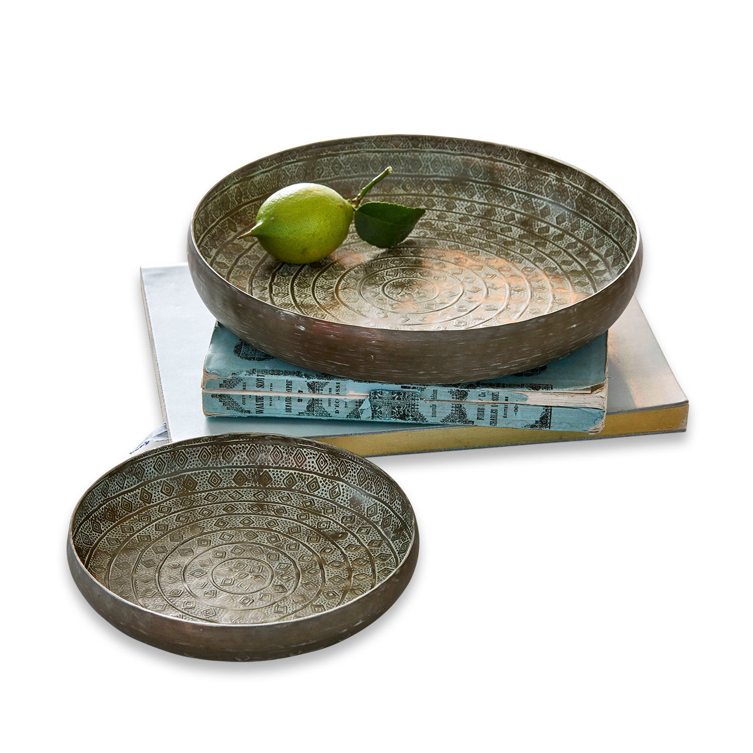 Set de 2 bandejas Birse Conjunto de dos cuencos metálicos con diseño decorativo en color plata envejecida sobre libros