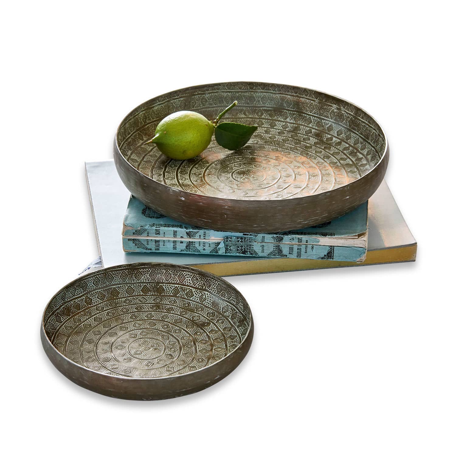 Set de 2 bandejas Birse Conjunto de dos cuencos metálicos con diseño decorativo en color plata envejecida sobre libros