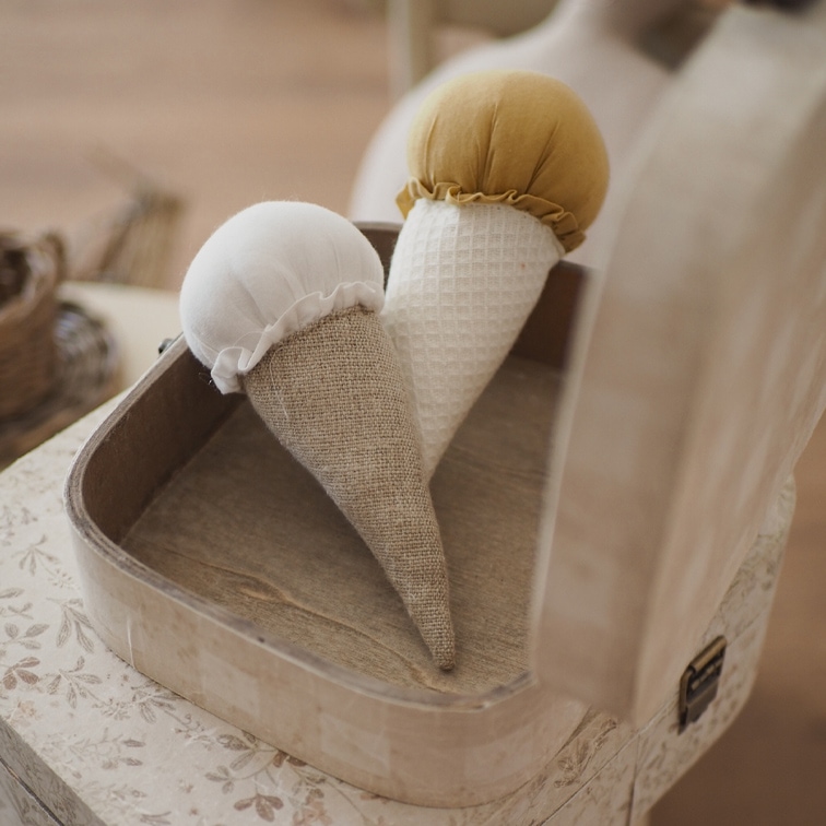 Dos conos decorativos de tela en blanco y mostaza en una caja de madera sobre la mesa