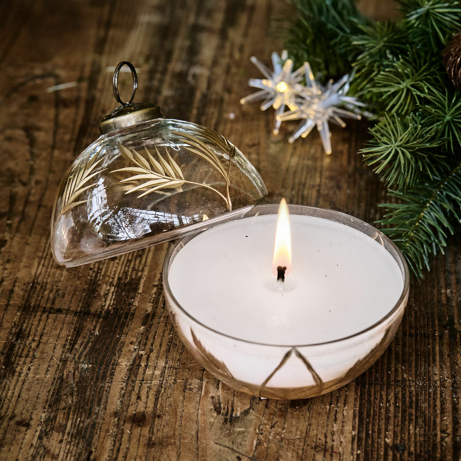 Portavelas con vela Belathor Vela aromática en recipiente de vidrio transparente con diseño dorado de hojas sobre mesa de madera
