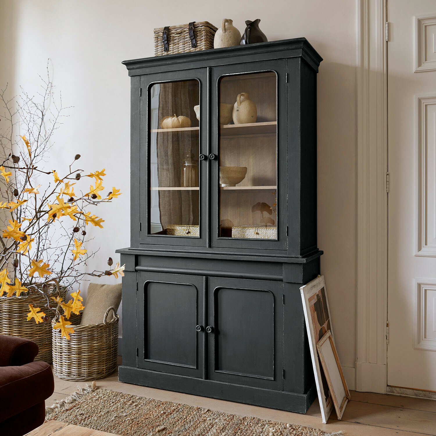 Vitrina Aldwyn Vitrina de madera negra con puertas de cristal y decoraciones de cerámica en sala de estar