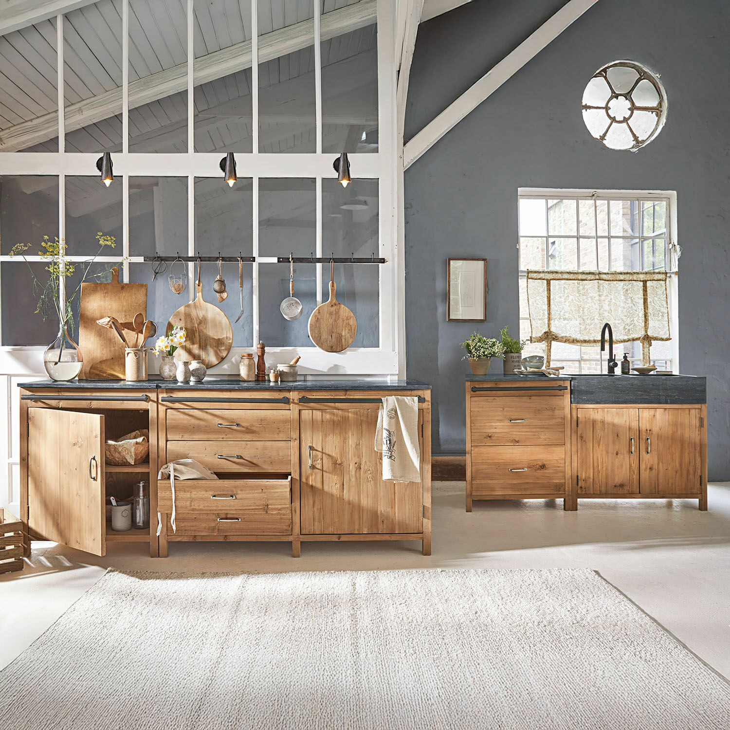 Set de 4 módulos de cocina Sunnybrook Cocina con muebles de madera y encimera negra en interior moderno y luminoso con grandes ventanas