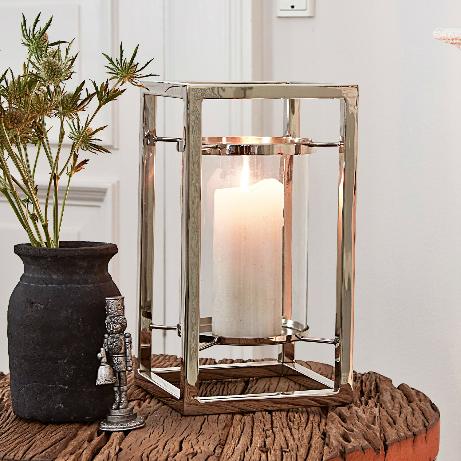 Portavelas moderno de acero inoxidable con vela blanca sobre mesa de madera para decoración interior