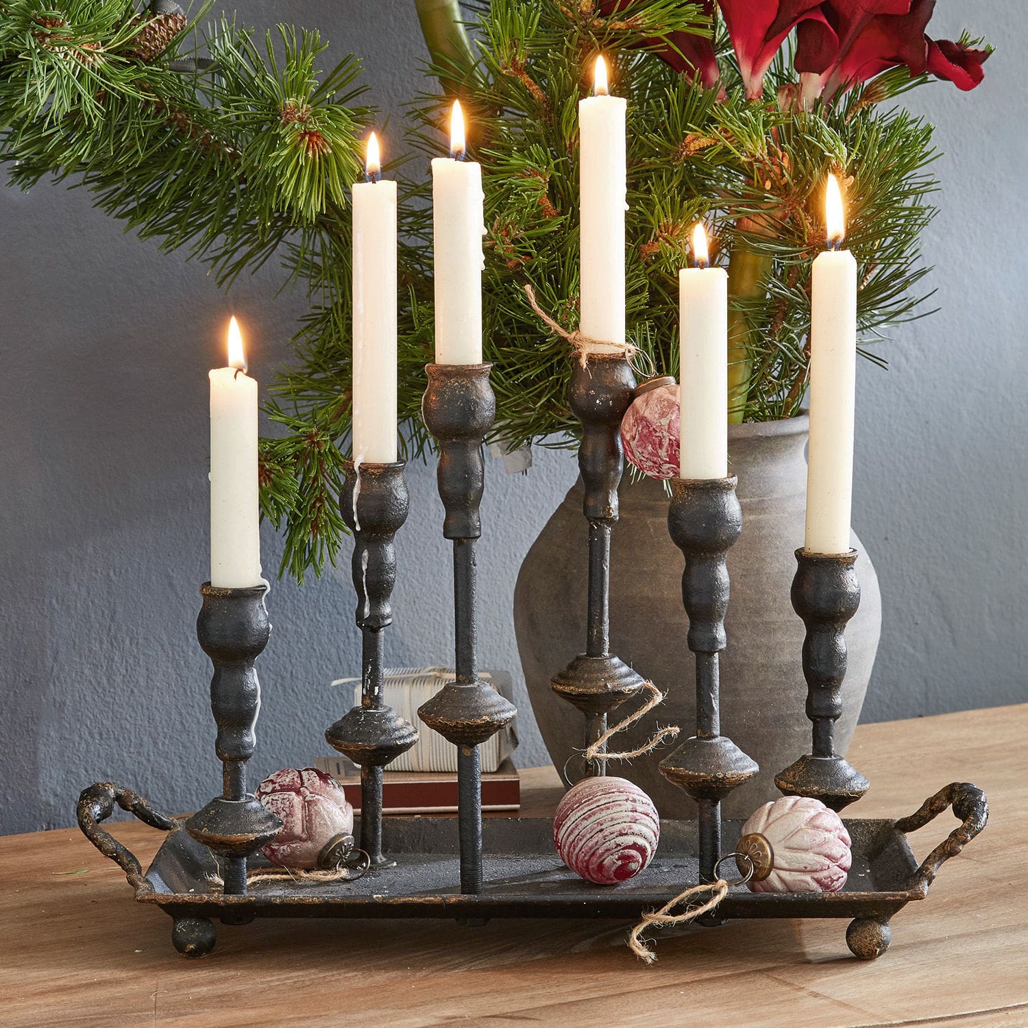 Candelabro Aisa Candelabro de metal negro con seis velas blancas y adornos navideños sobre mesa de madera