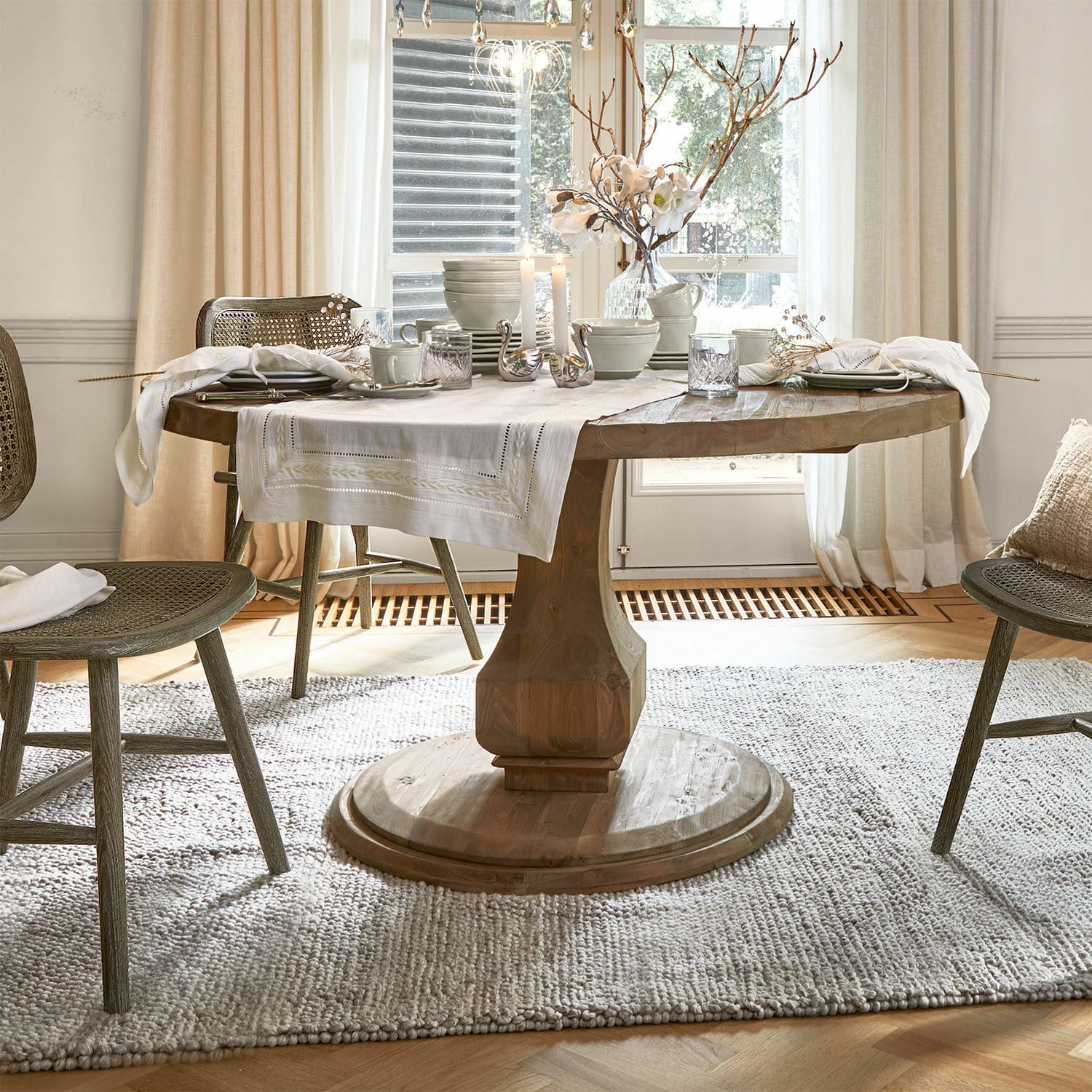 Mesa Alderwick Mesa redonda de madera con mantel blanco y decoración en comedor luminoso y acogedor con luz natural