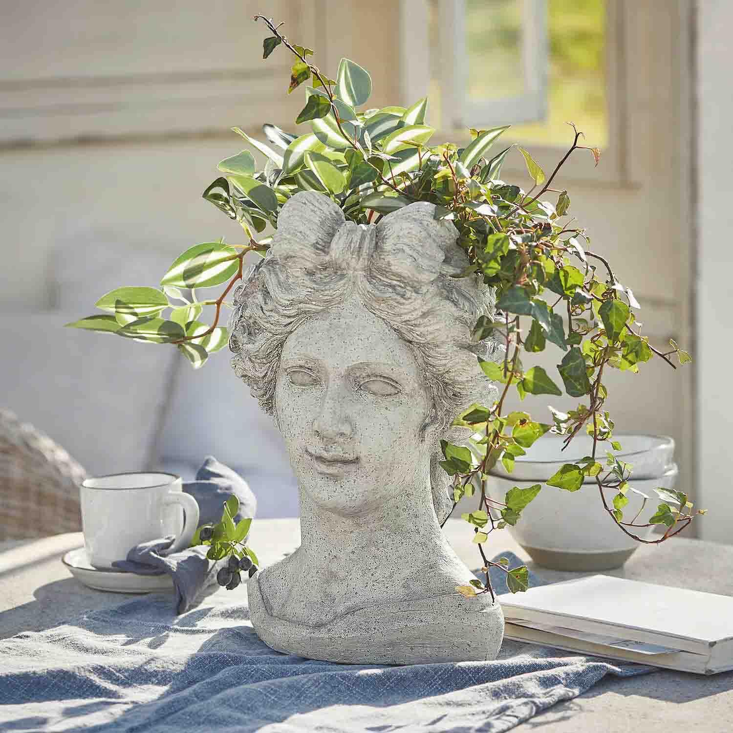 Maceta en forma de cabeza de mujer de piedra gris con plantas verdes, decoración para jardín