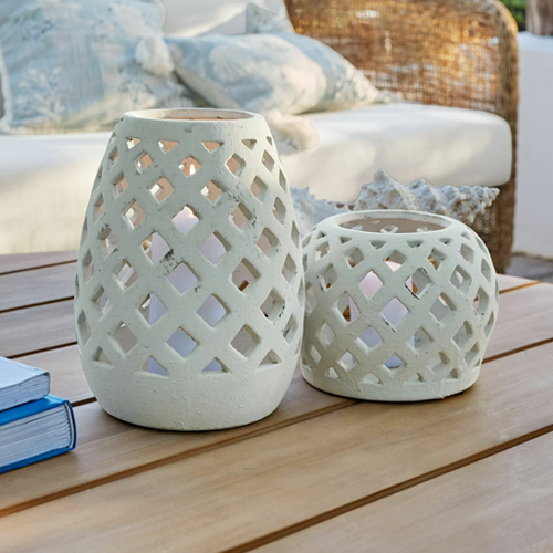 Dos faroles blancos de cerámica con diseño calado sobre mesa de madera, decoración de jardín