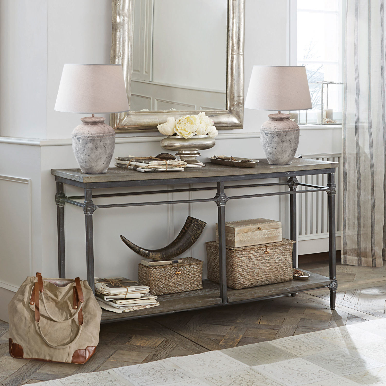 Consola Caspian Consola vintage de madera y metal con lámparas y decoraciones beige en un interior luminoso y elegante