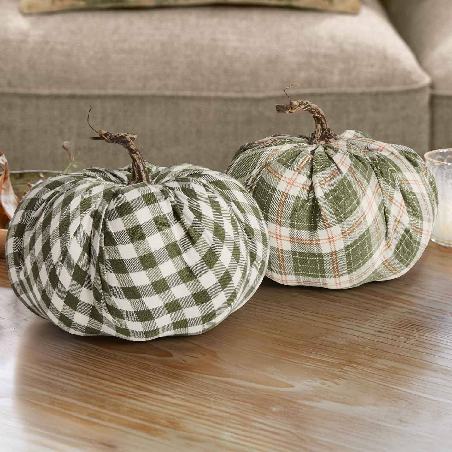 Dos calabazas decorativas de tela a cuadros verde y blanco con tallos naturales sobre mesa de madera