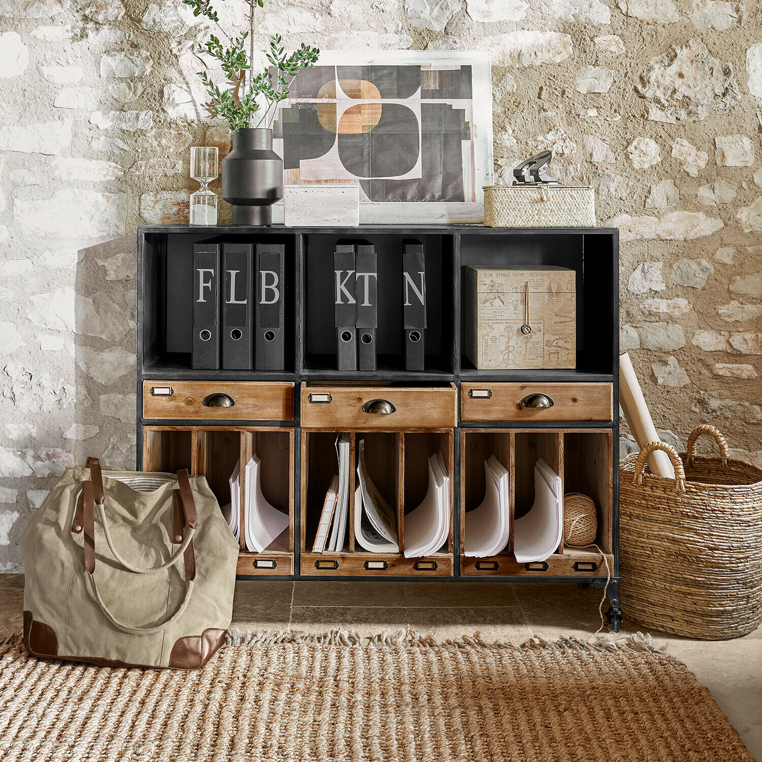Mueble negro de metal y madera con cajones y archivadores frente a pared de piedra estilo vintage