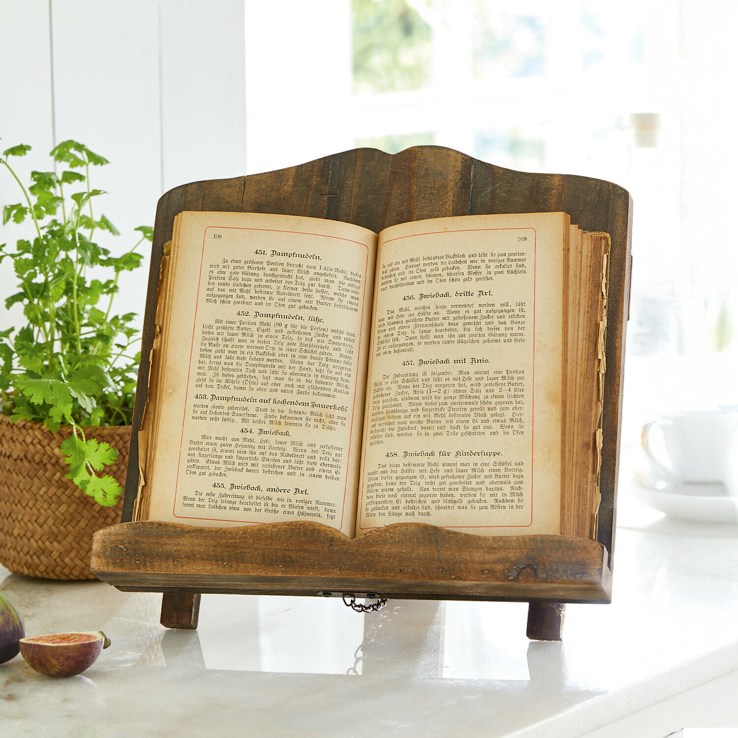 Sujetalibros Mags Soporte rústico de madera para libro de cocina sobre encimera de mármol con higos y planta verde