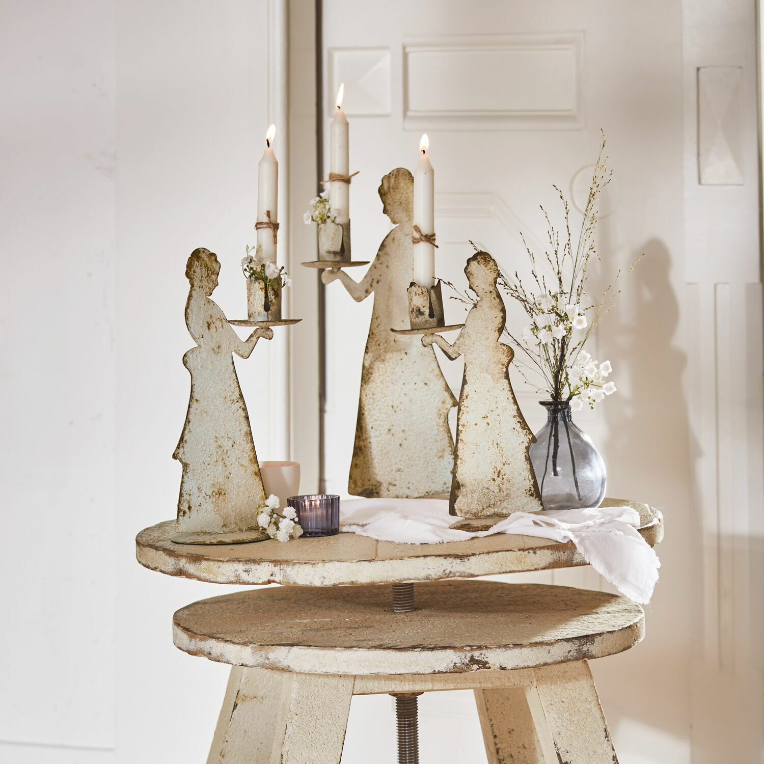 Set de 3 candeleros Chanler Candelabros de metal con forma de mujer y velas blancas sobre mesa rústica decorativa