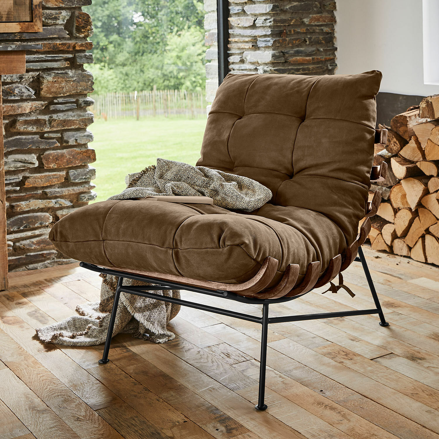 Sillón Horraine Sillón marrón con tapizado suave y estructura metálica sobre suelo de madera en interior acogedor