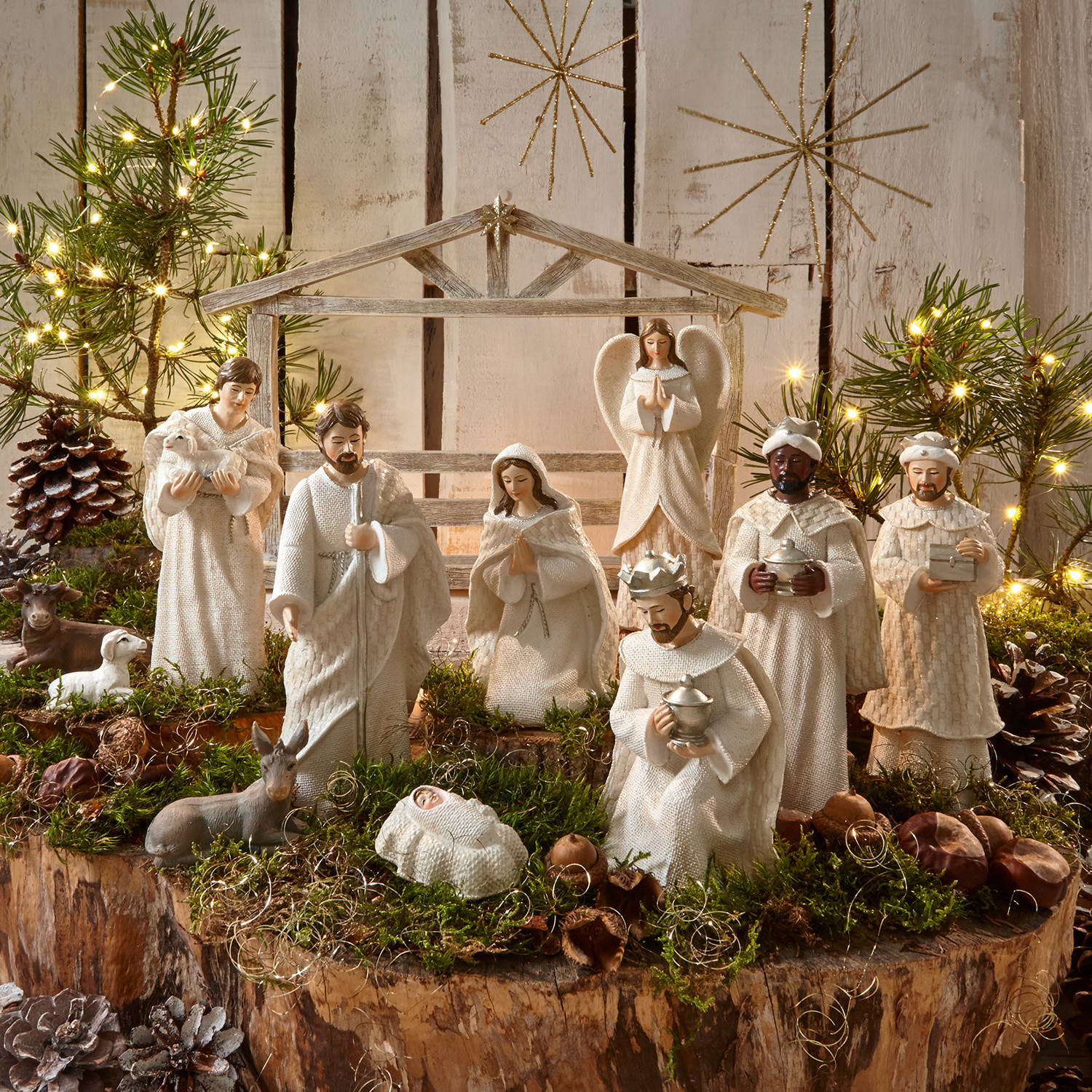 Set de 12 figuras de belén Santo Conjunto de figuras blancas de pesebre navideño de madera y tela sobre fondo natural con musgo y luces