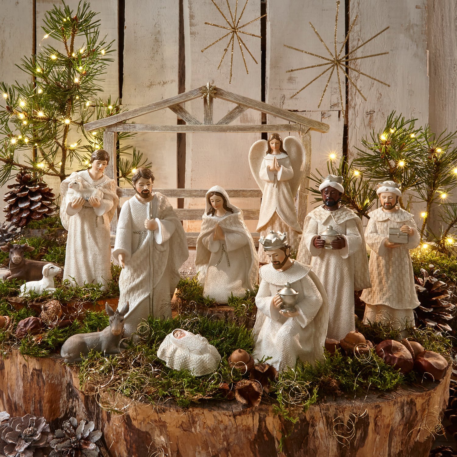 Set de 12 figuras de belén Santo Conjunto de figuras blancas de pesebre navideño de madera y tela sobre fondo natural con musgo y luces