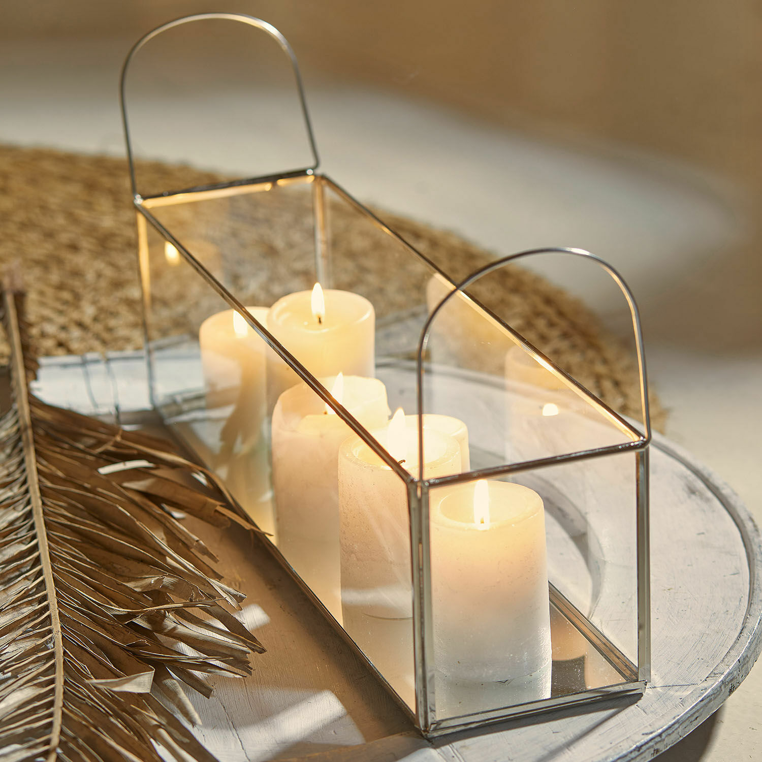Linterna Quinton Linterna rectangular de metal con espejo y velas blancas sobre mesa decorativa