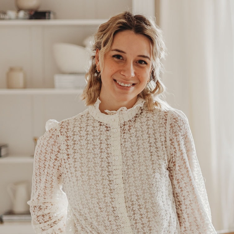 Mujer con blusa blanca de encaje con patrón floral en interior luminoso