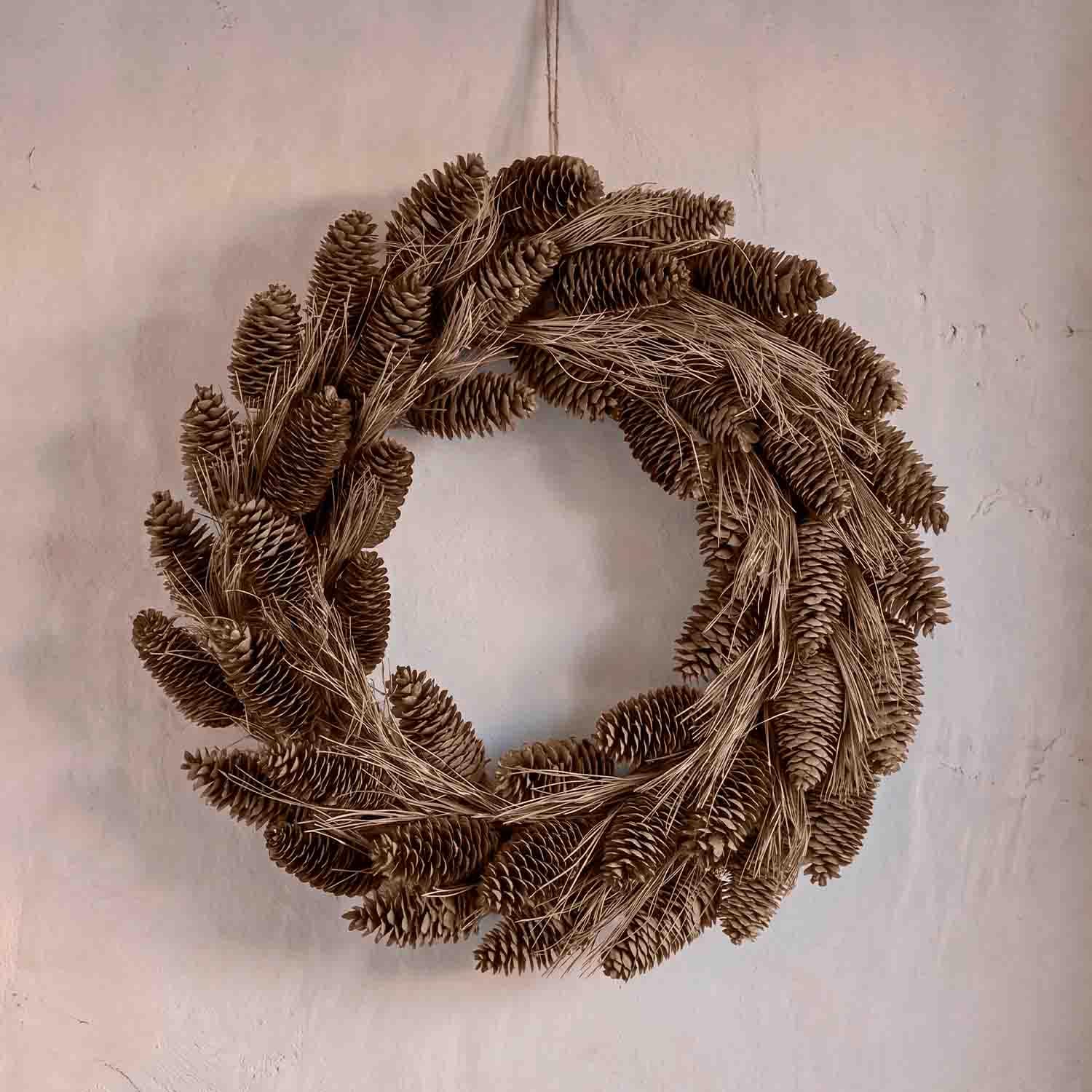 Corona decorativa natural de piñas y hierbas secas marrones para colgar en la pared