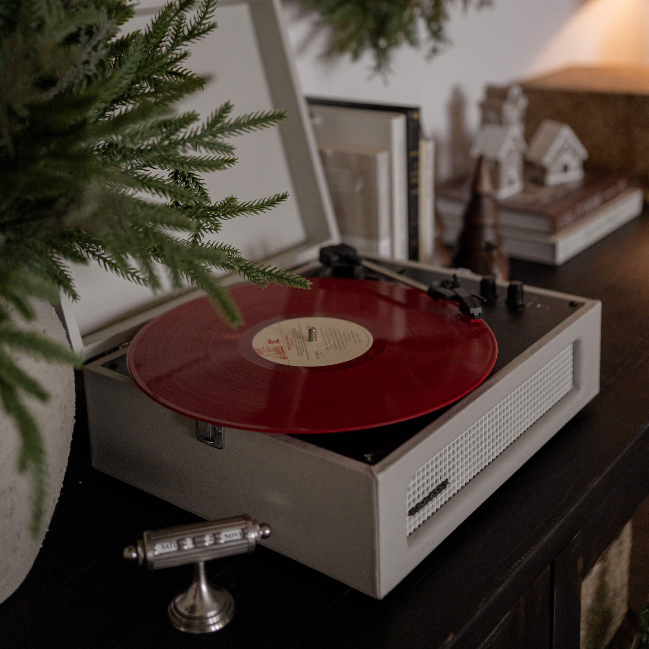 Tocadiscos retro con disco de vinilo rojo sobre mueble oscuro en ambiente acogedor