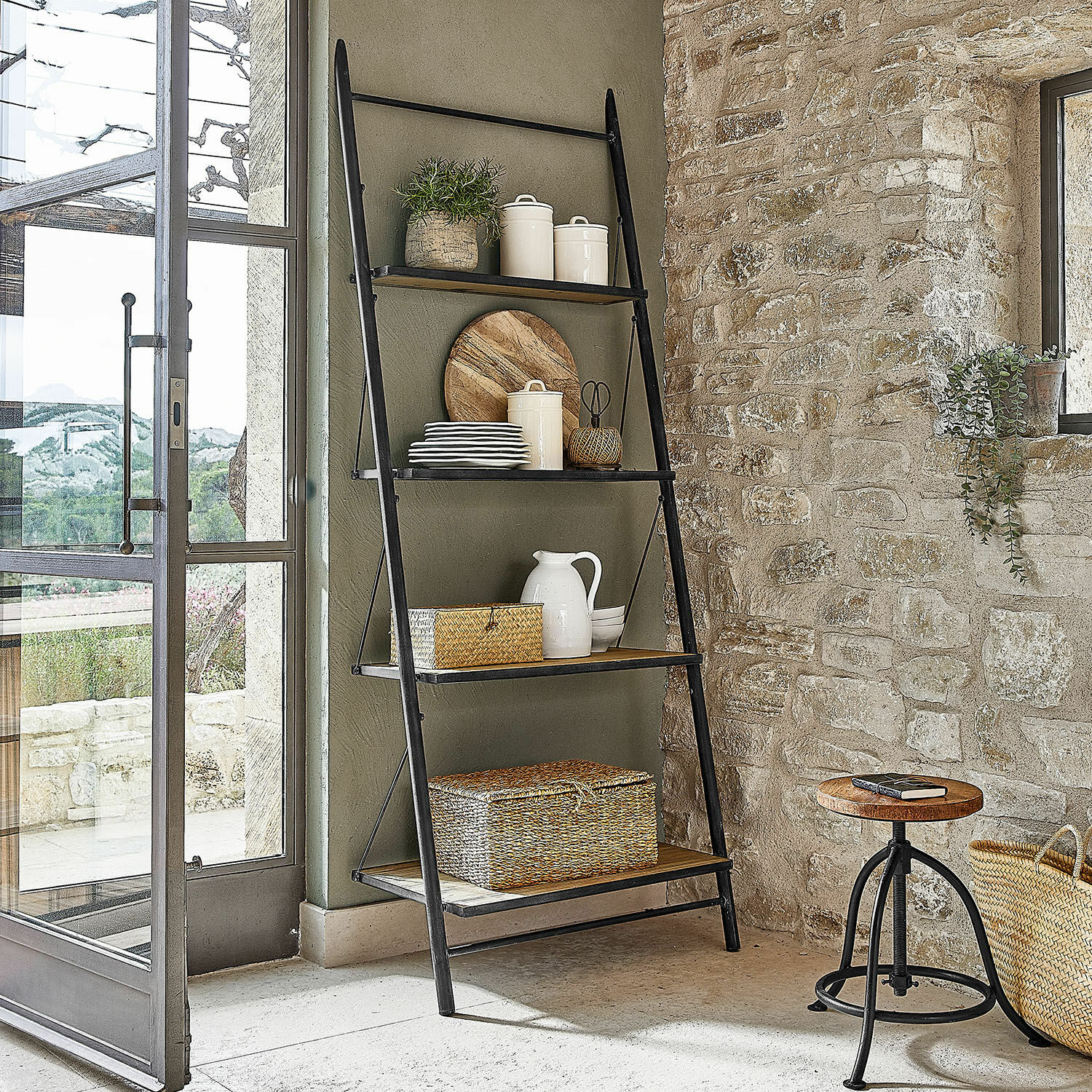 Estante Greenbriar Escalera negra de metal con estantes de madera y decoraciones en interior rústico con pared de piedra