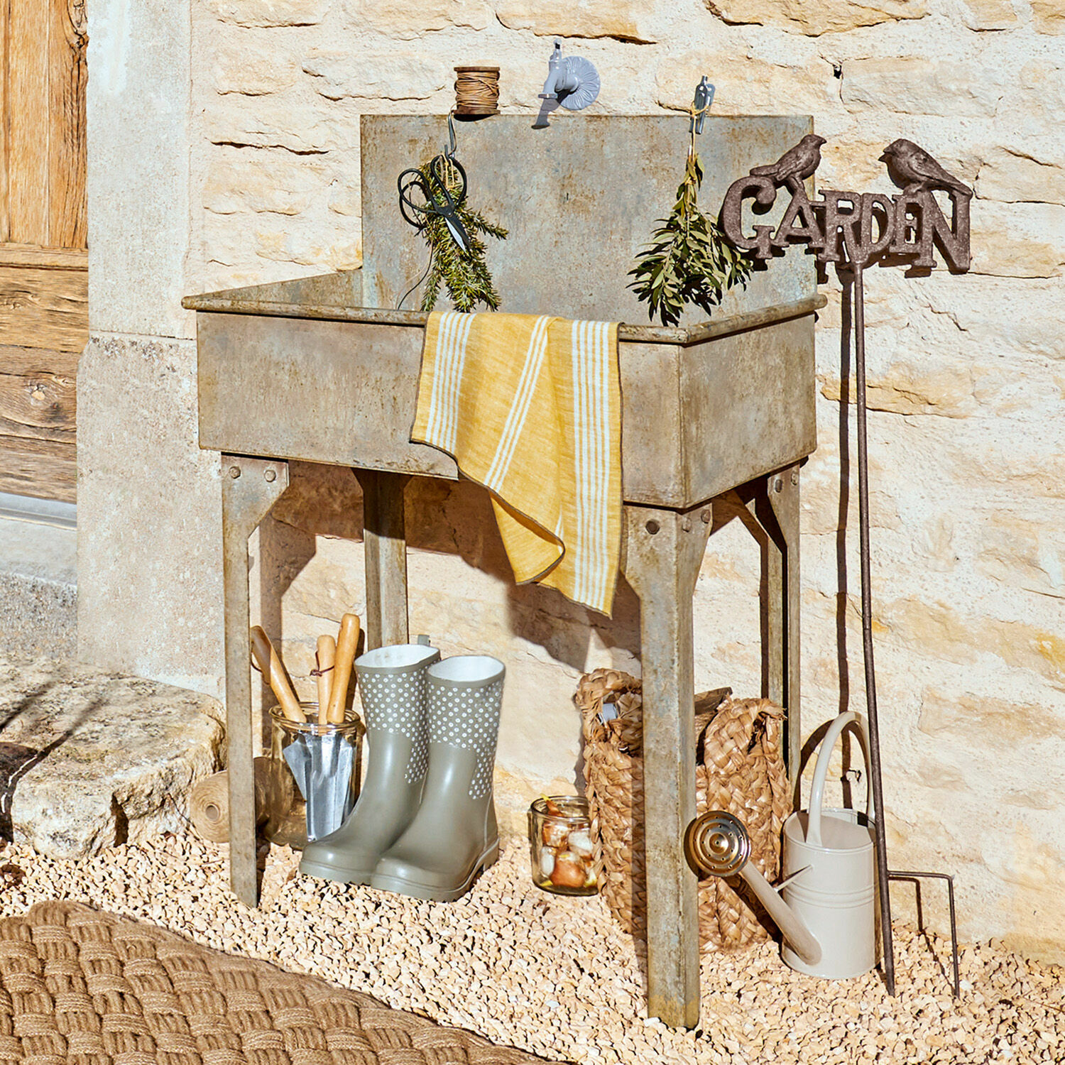 Lavabo para exterior Lison Fregadero de jardín metálico gris con herramientas y botas de goma sobre suelo de grava
