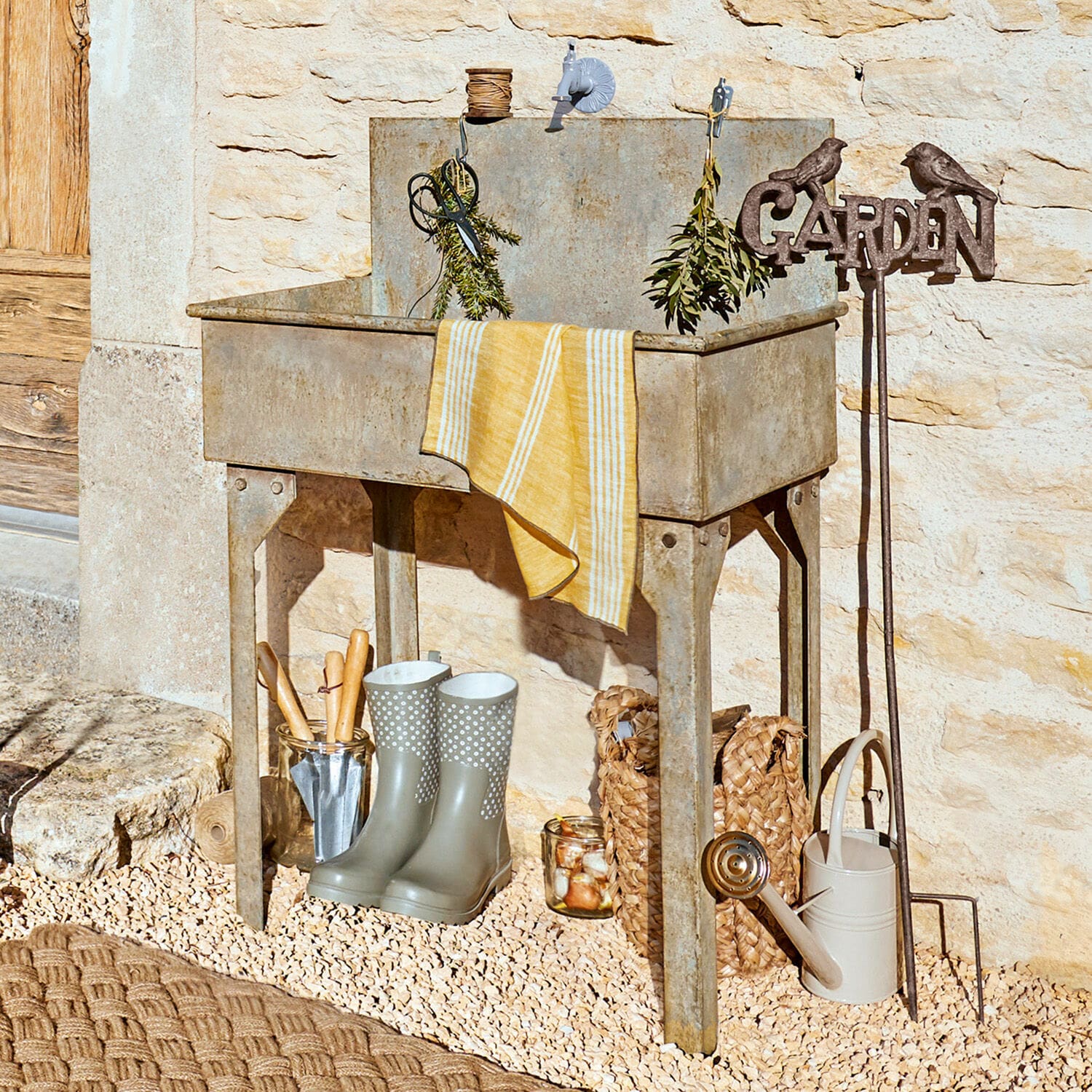 Lavabo para exterior Lison Fregadero de jardín metálico gris con herramientas y botas de goma sobre suelo de grava