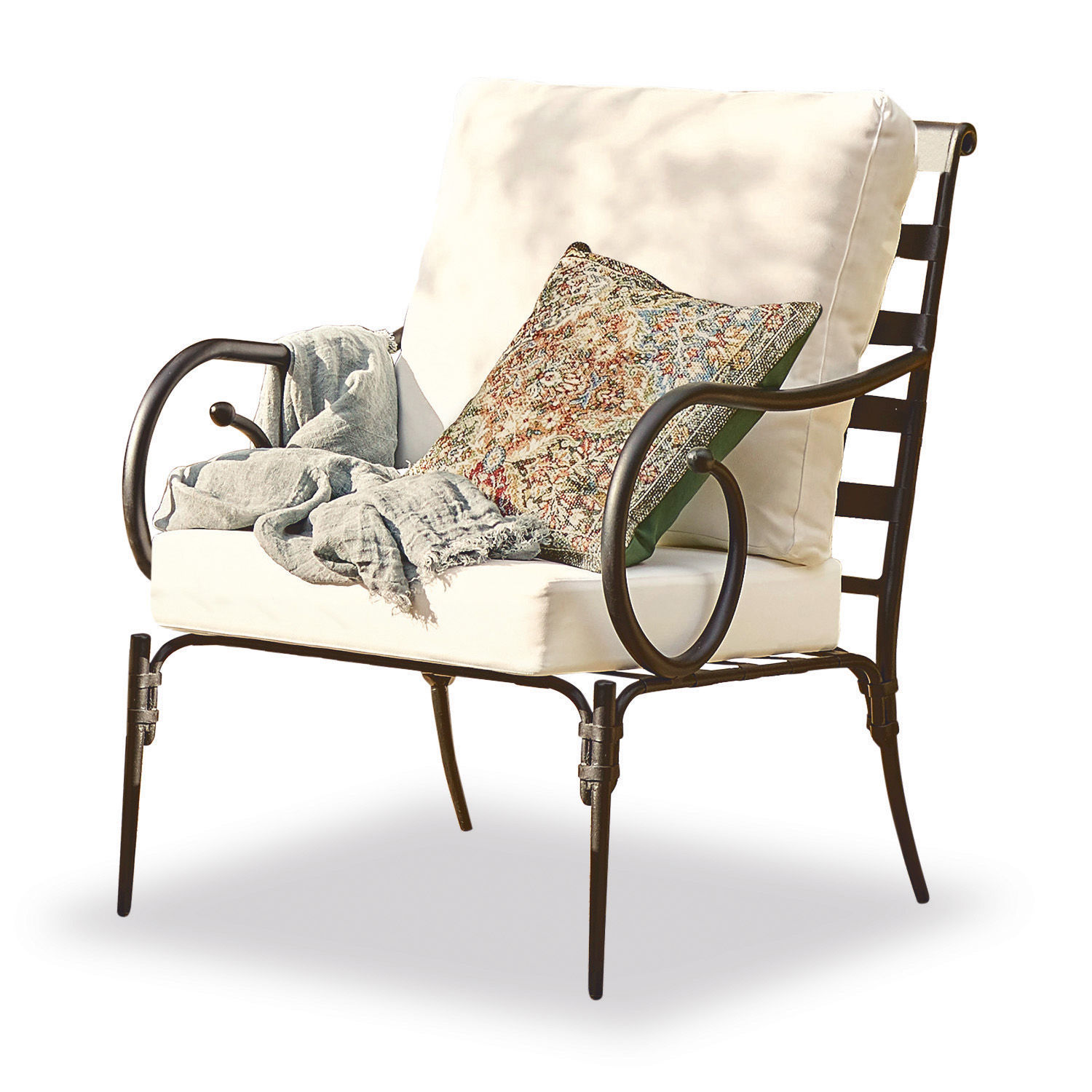 Sillón de metal con cojines crema y cojín decorativo con estampado colorido