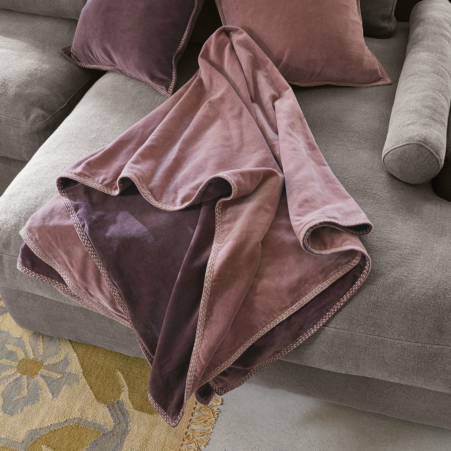 Plaid Murs Manta reversible de terciopelo suave en tonos rosa y violeta sobre sofá gris, textil decorativo para salón