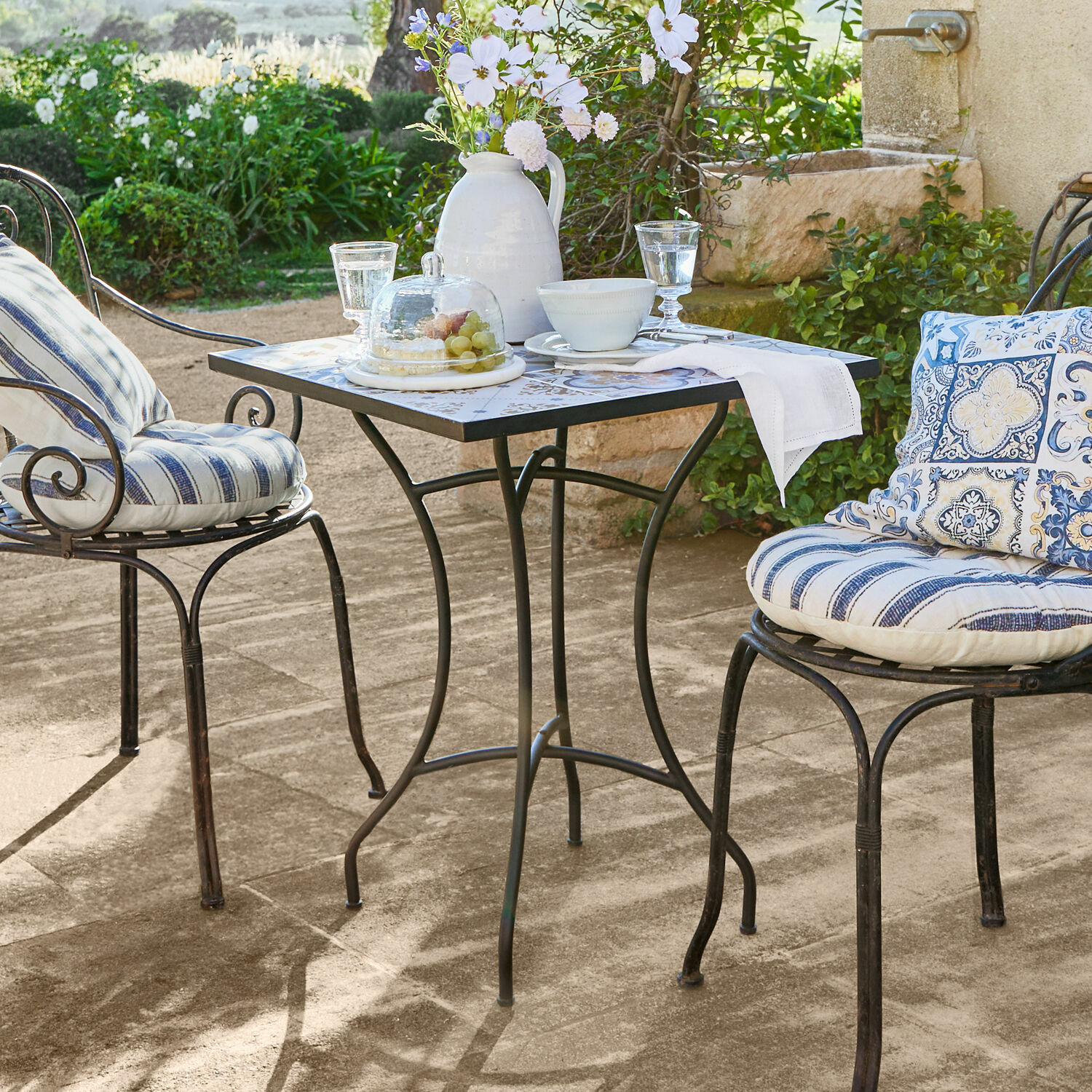 Mesa Céligny Mesa de jardín de metal con tablero cuadrado y dos sillas con cojines a rayas azules