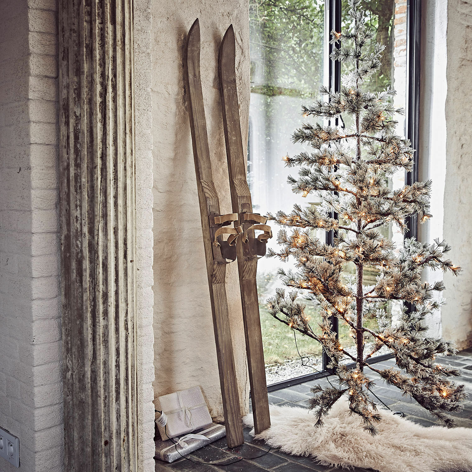 Set de 2 esquís decorativos Lambeth Esquís de madera vintage junto a árbol de Navidad artificial iluminado con alfombra blanca