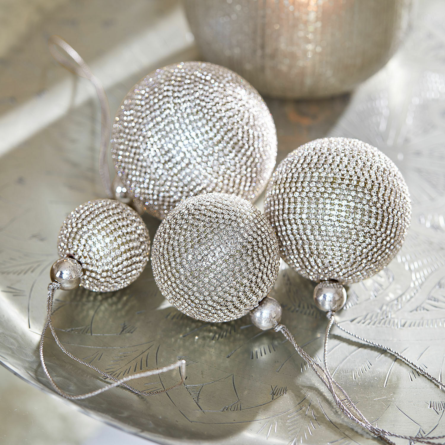 Set de 4 bolas de Navidad Varnor Conjunto de cuatro bolas navideñas plateadas con pequeños cristales sobre bandeja metálica decorativa