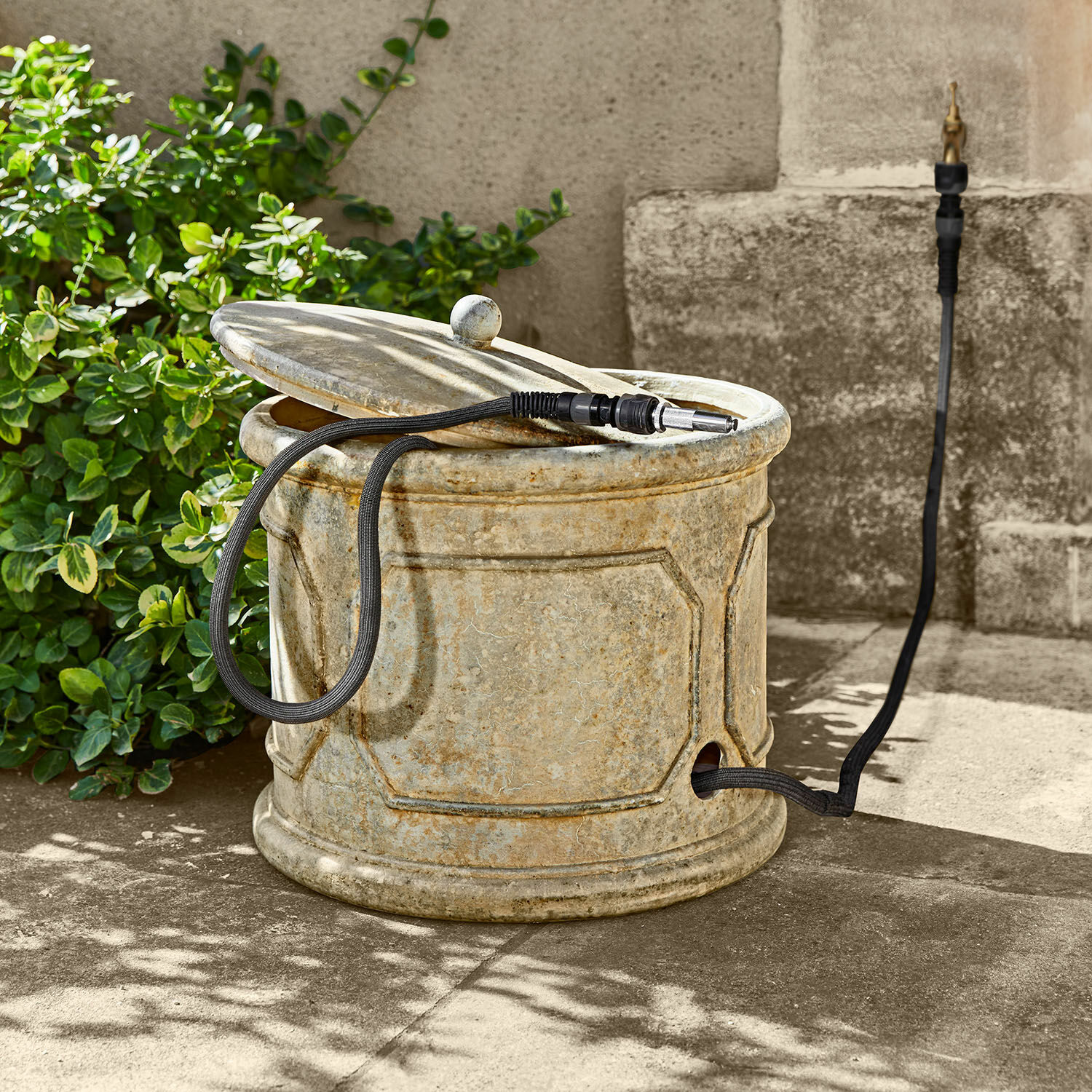 Recipiente para manguera de jardín Filervo Contenedor de jardín redondo de piedra beige con manguera negra para riego