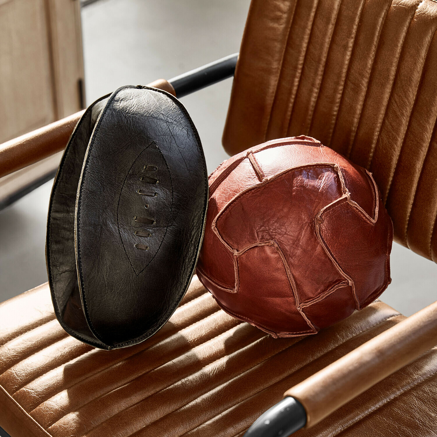 Set de 2 balones decorativos Awanian Balón de ejercicio marrón y negro de cuero natural sobre sillón de cuero marrón