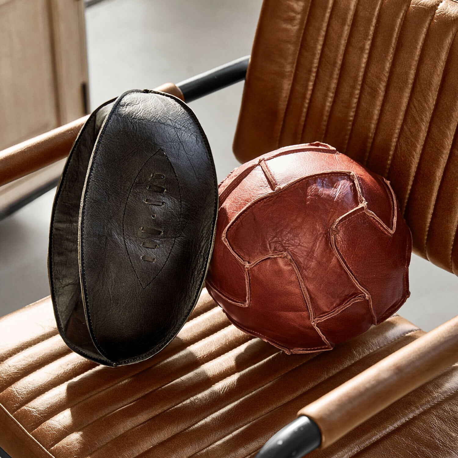 Set de 2 balones decorativos Awanian Balón de ejercicio marrón y negro de cuero natural sobre sillón de cuero marrón