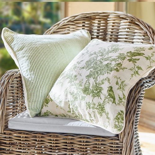 Dos cojines decorativos verdes de algodón en una silla de mimbre, estilo rústico, textiles para el hogar