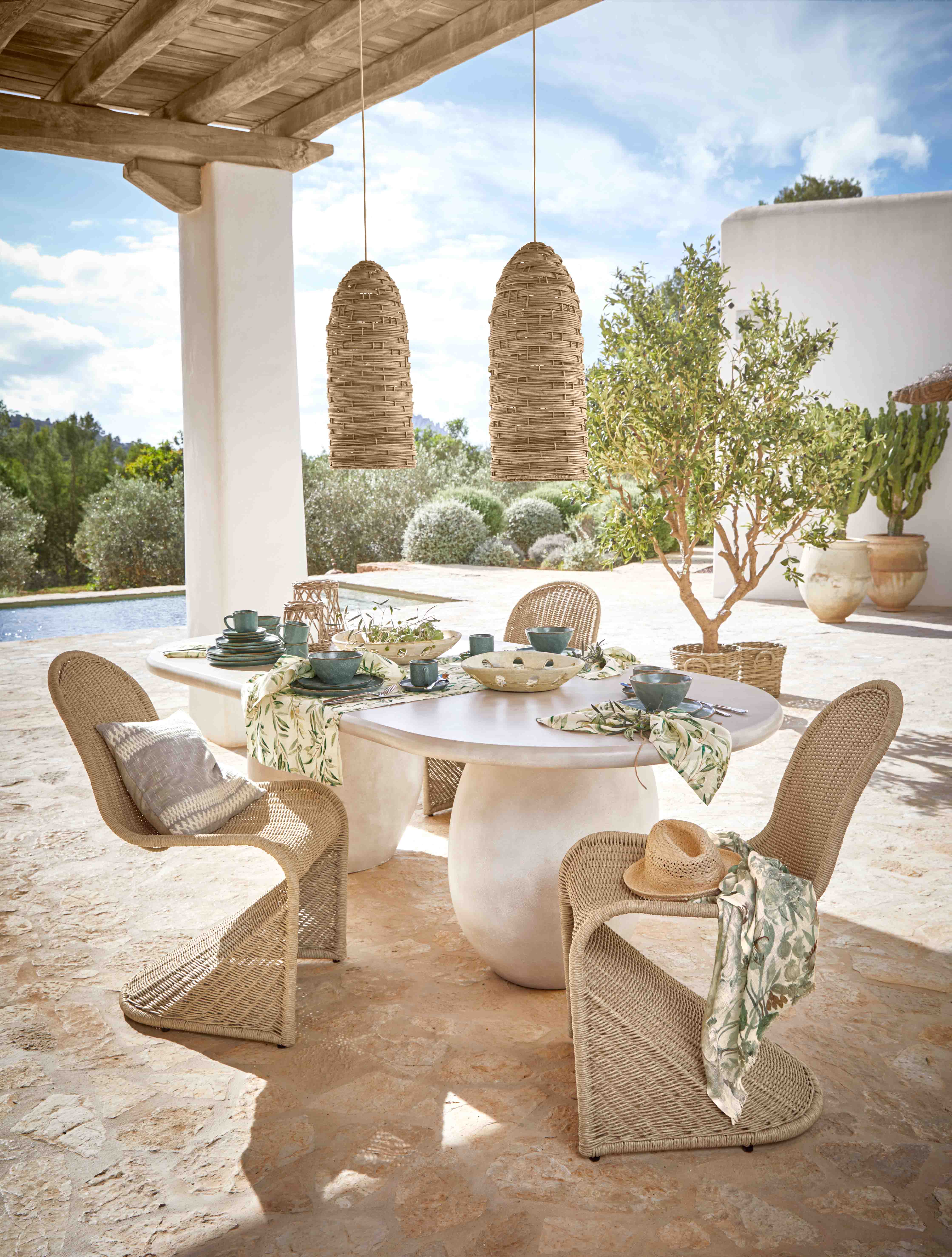 Conjunto de muebles de jardín de mimbre con sillas y mesa blanca en terraza con decoración de mesa