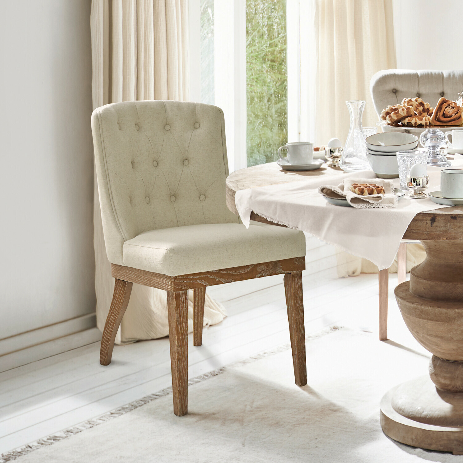 Silla Fairwyn Silla tapizada beige con patas de madera junto a mesa de comedor con vajilla y pasteles