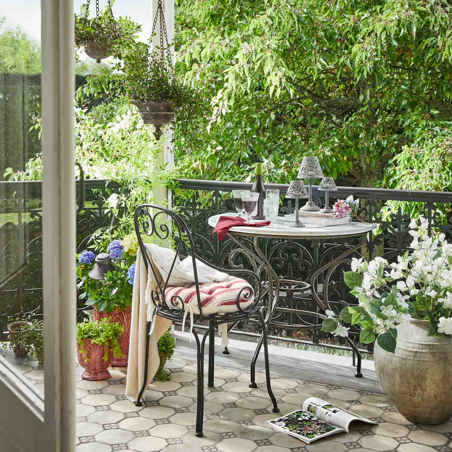 Balcón con mesa y silla de metal, plantas en macetas y ambiente relajante al aire libre