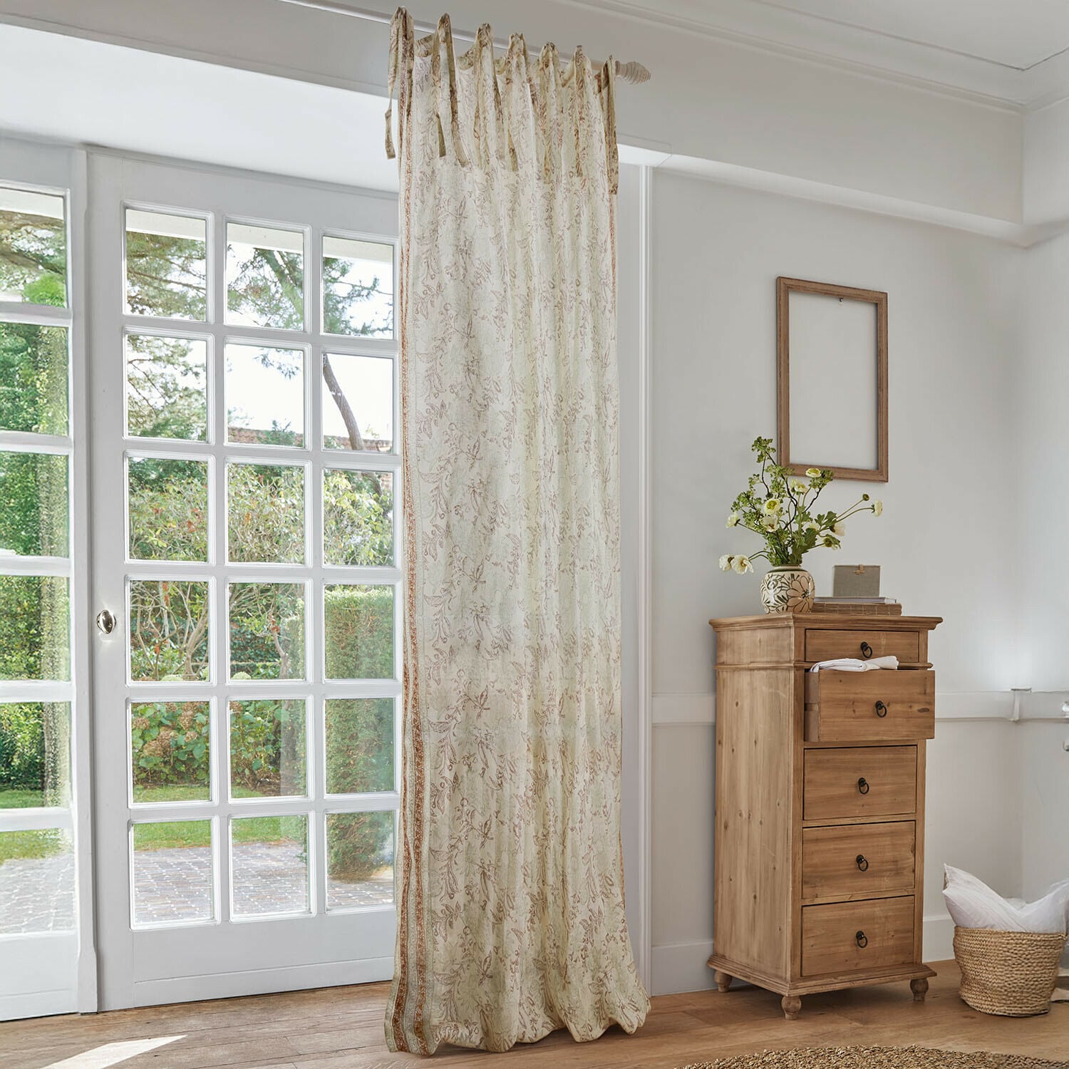 Cortina Floréane Cortina beige con delicado estampado floral en salón luminoso con cómoda de madera y ventana grande