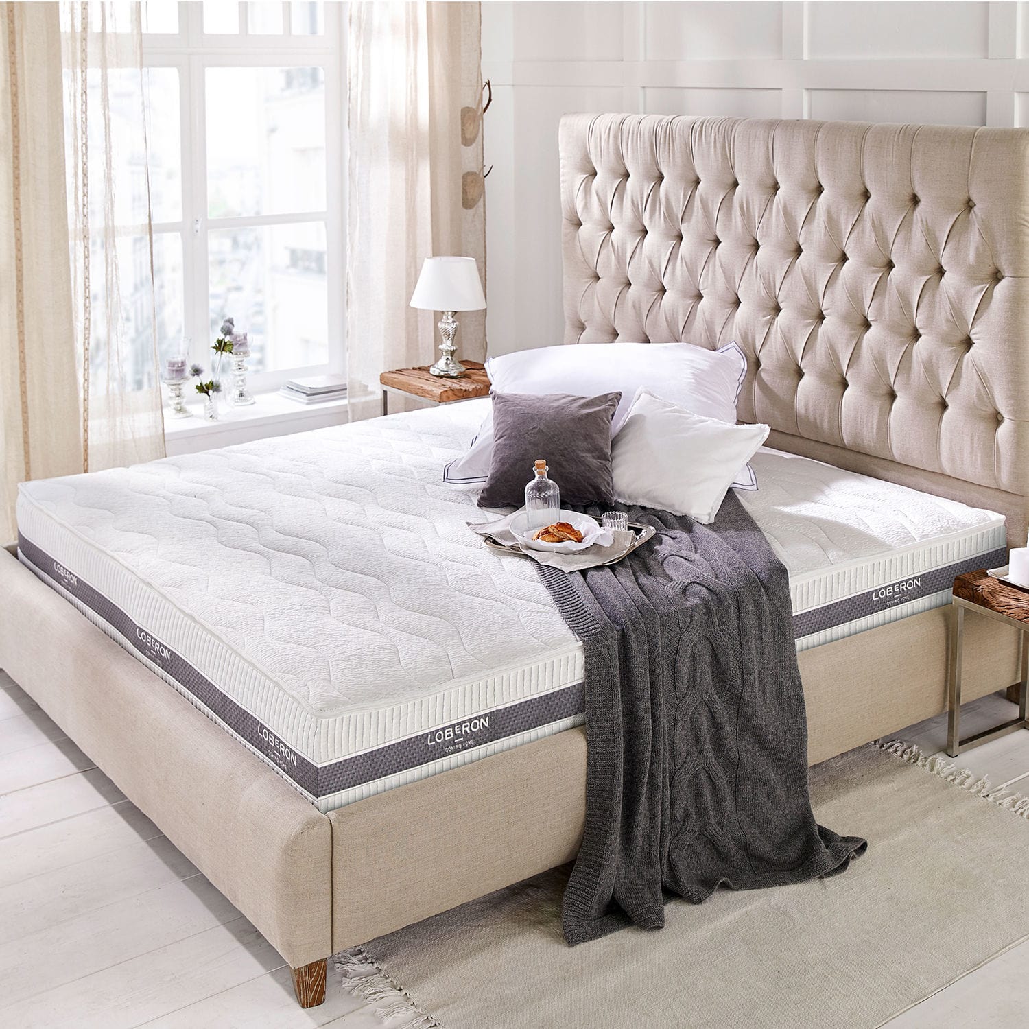 Colchón 180x200 Turim Colchón blanco moderno Loberon sobre cama beige con cabecero capitoné en habitación luminosa