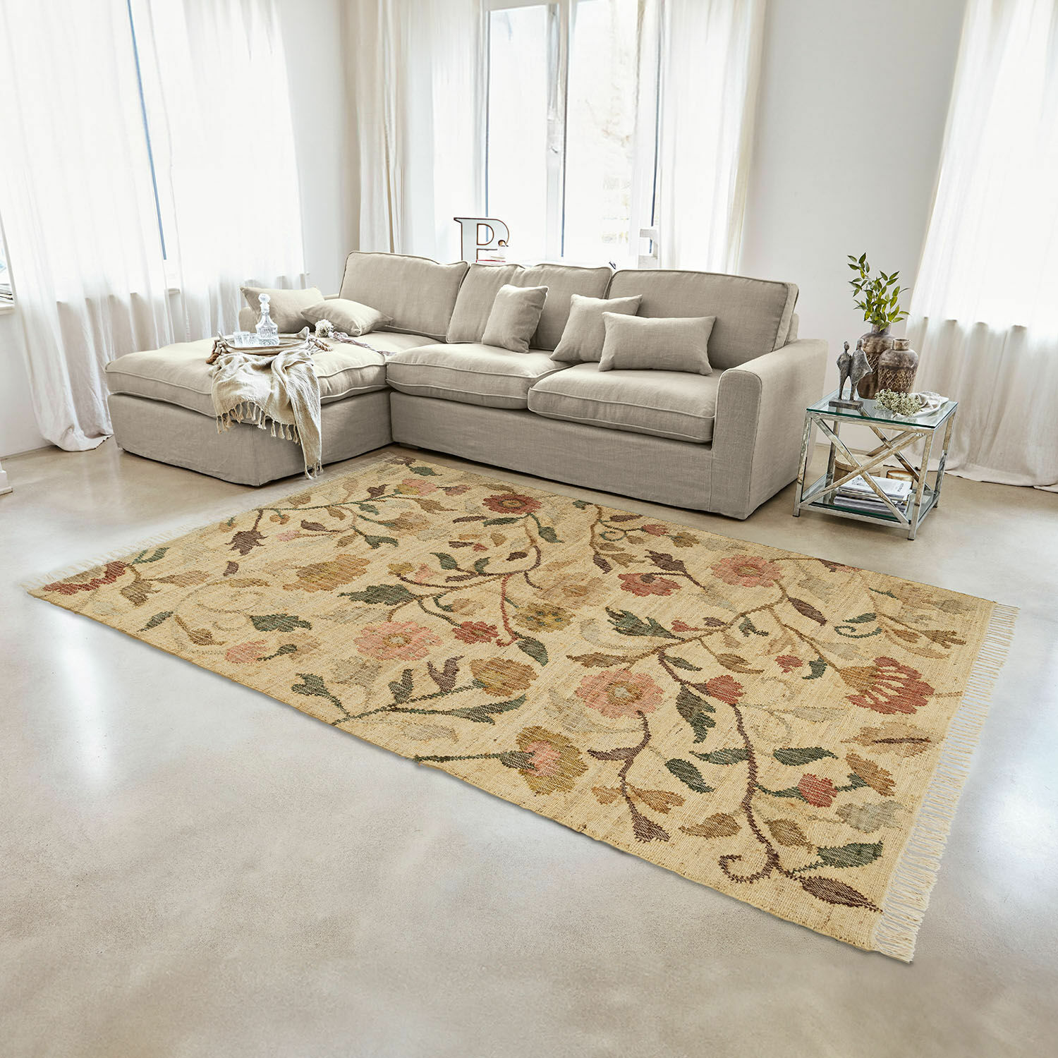 Alfombra Théranelle Alfombra beige de lana con diseño floral en sala con sofá gris y mesa auxiliar de cristal