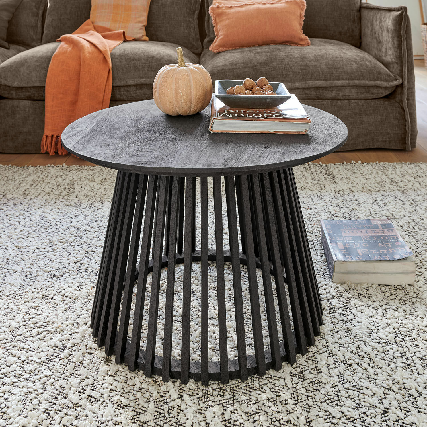 Mesa de centro Montaril Mesa de centro redonda negra de madera de mango con base abierta sobre alfombra clara en sala de estar