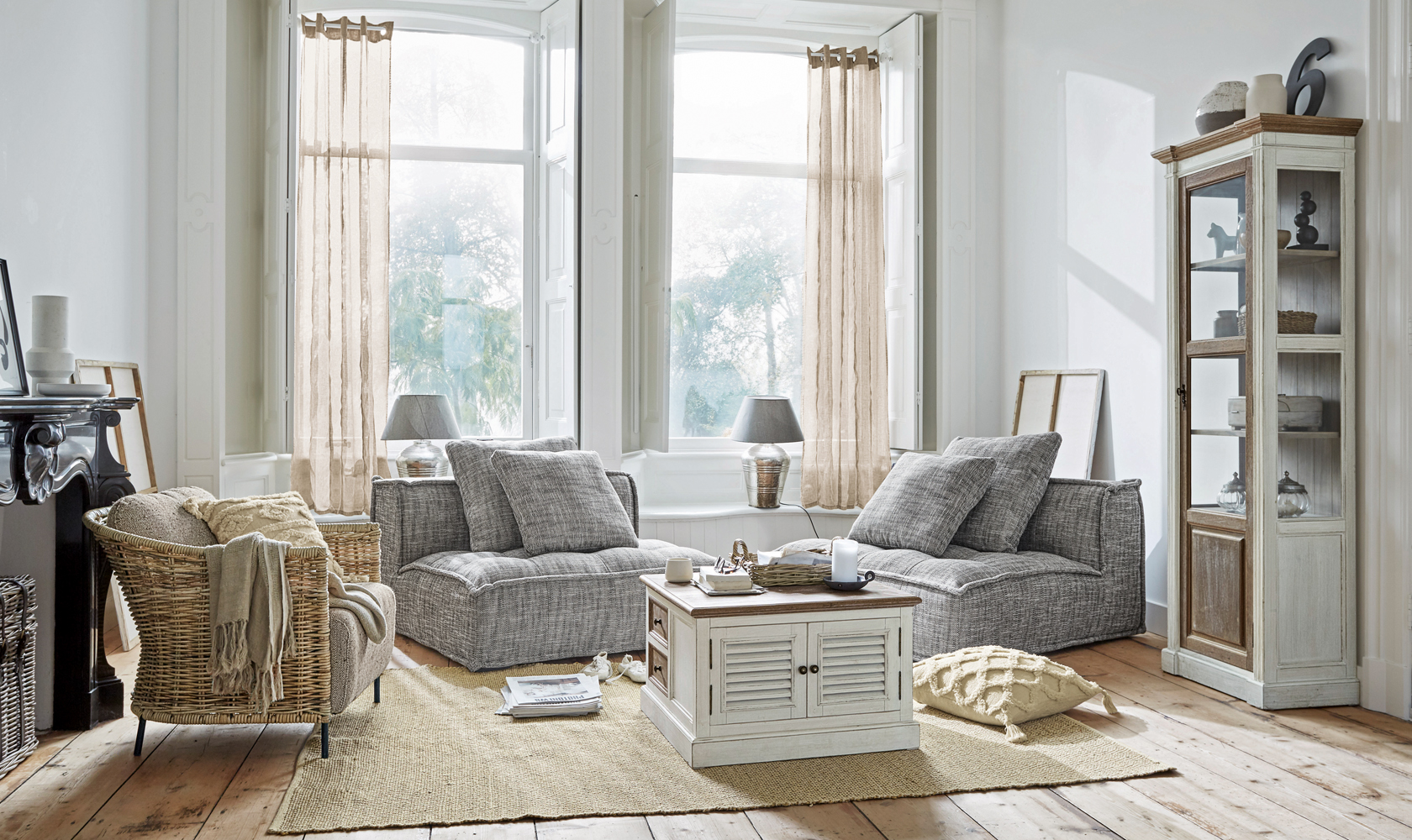 Salón acogedor con sillones grises y mueble blanco de madera sobre alfombra de yute, estilo escandinavo