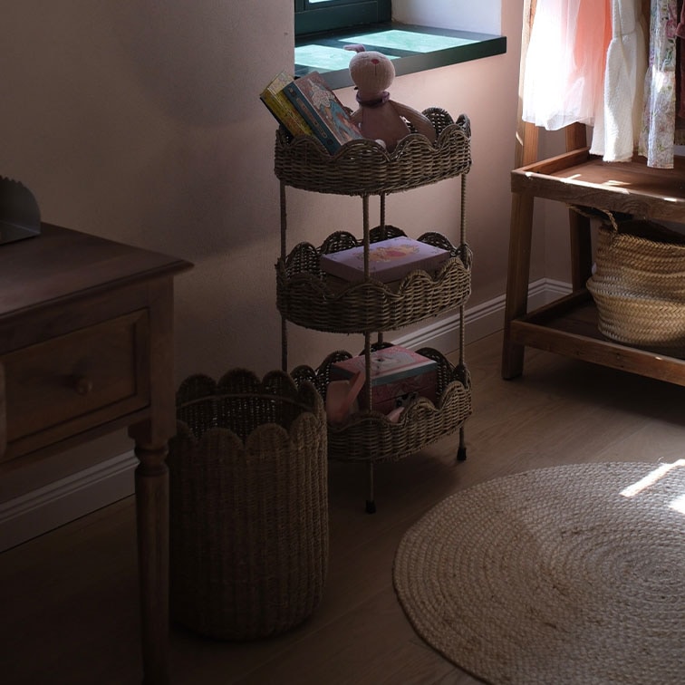 Estantería de mimbre natural de tres niveles con libros y juguetes en habitación acogedora