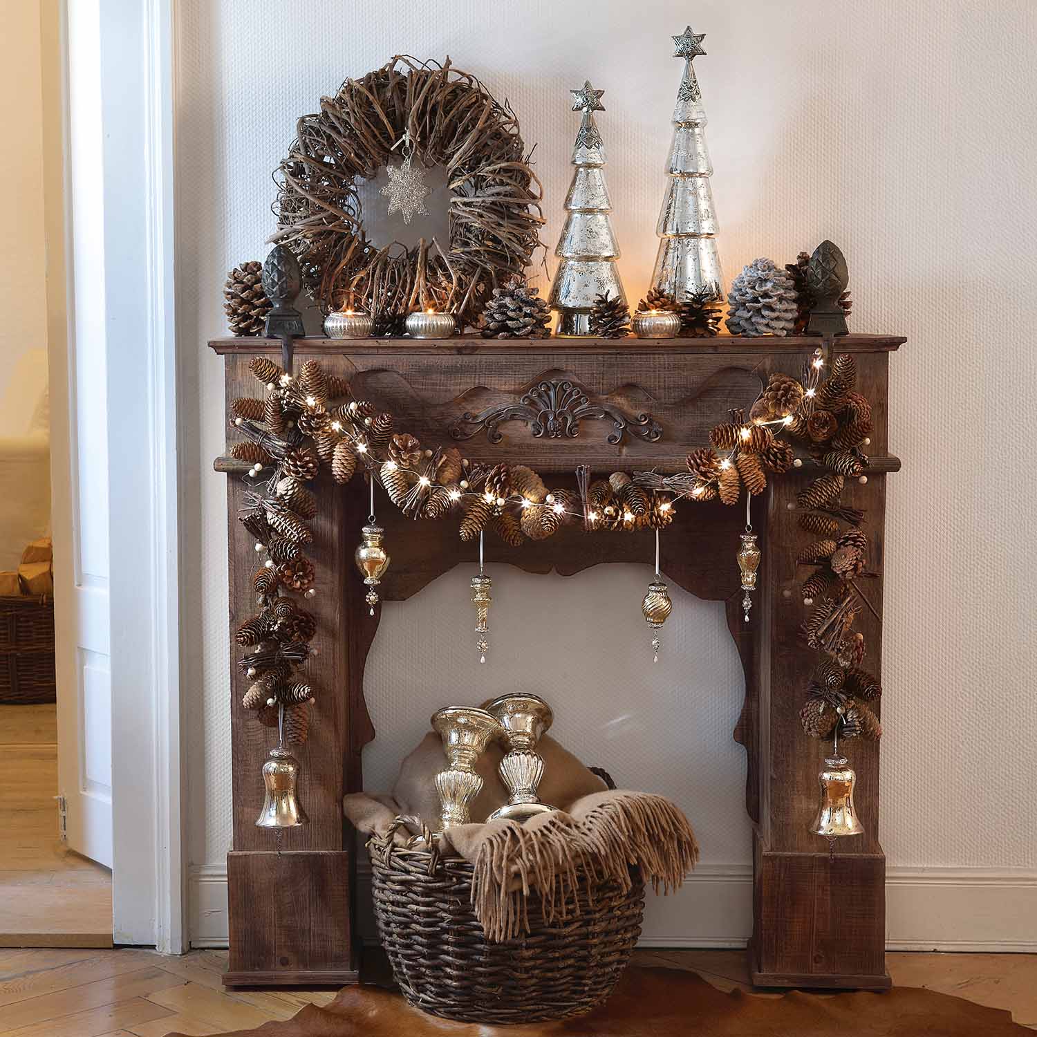 Chimenea rústica de madera decorada con piñas, luces y adornos navideños plateados