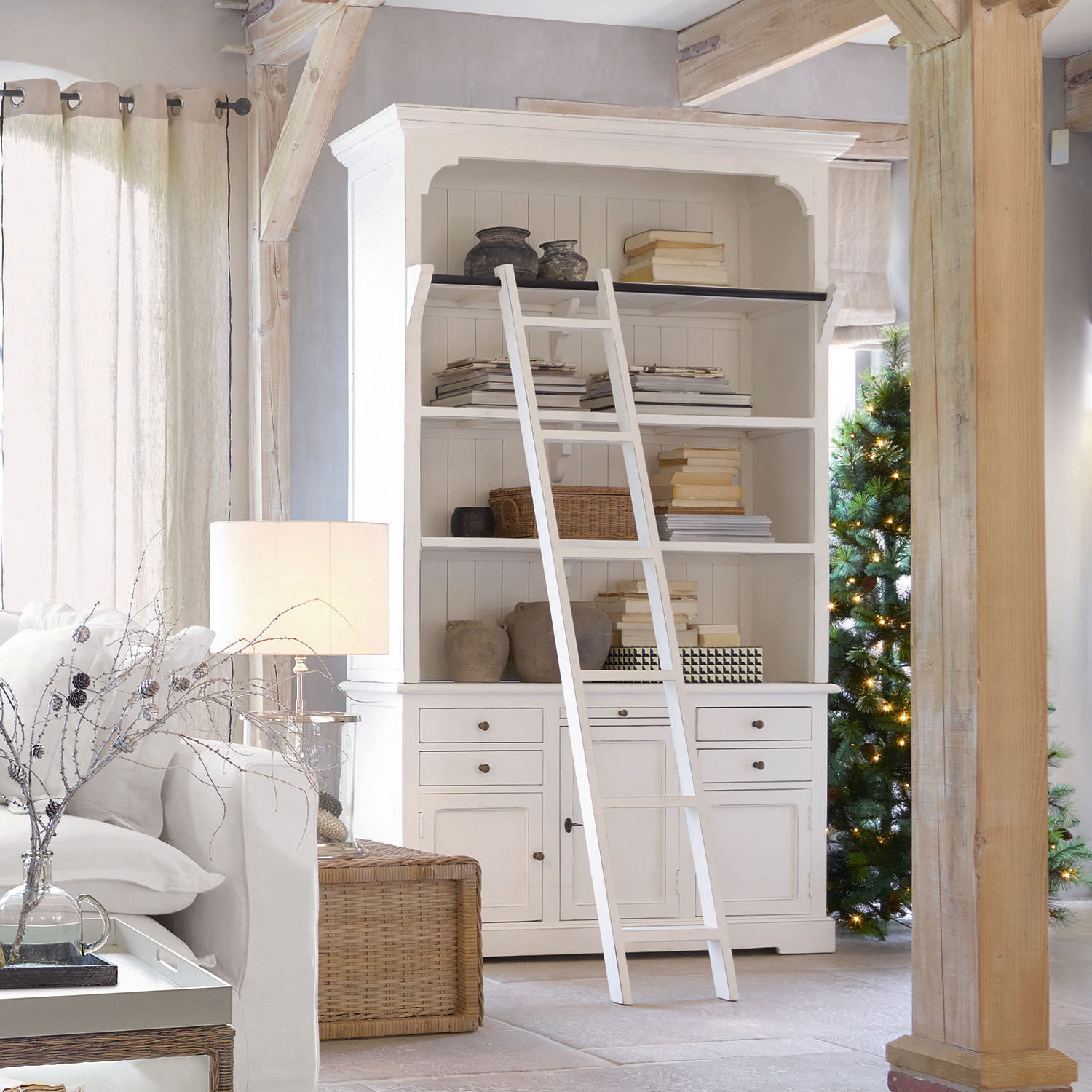 Armario Monts Librería blanca de madera con escalera y decoraciones en salón luminoso con luz natural